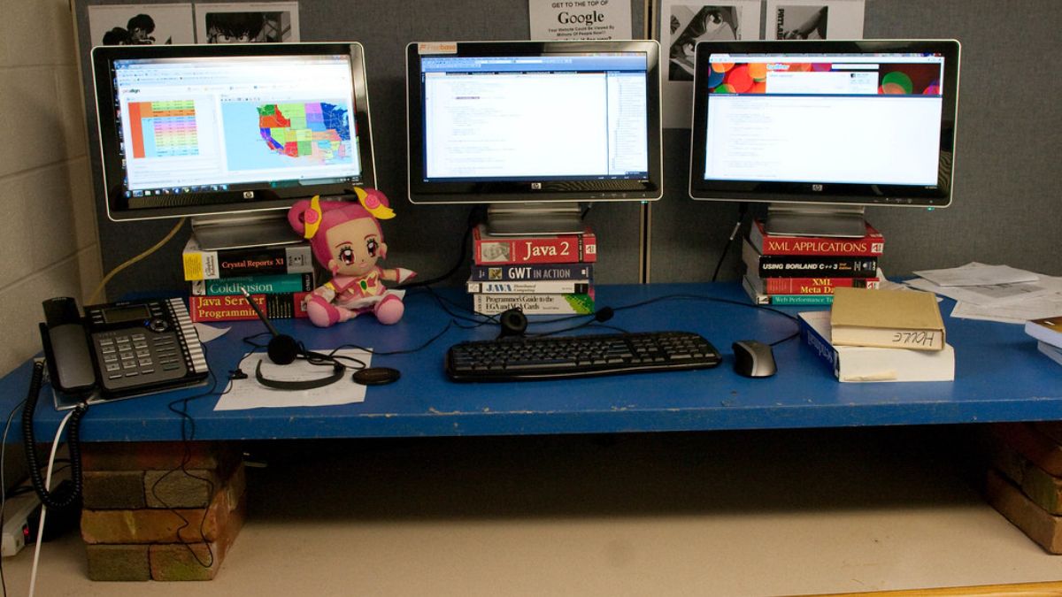Layar monitor dan laptop di meja kerja kantor.