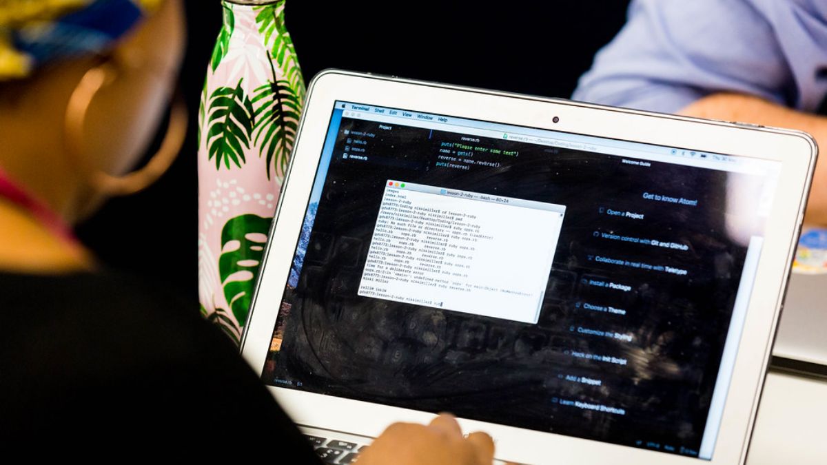 Seseorang sedang mengetik kode pemrograman pada laptop dalam sesi pembelajaran.
